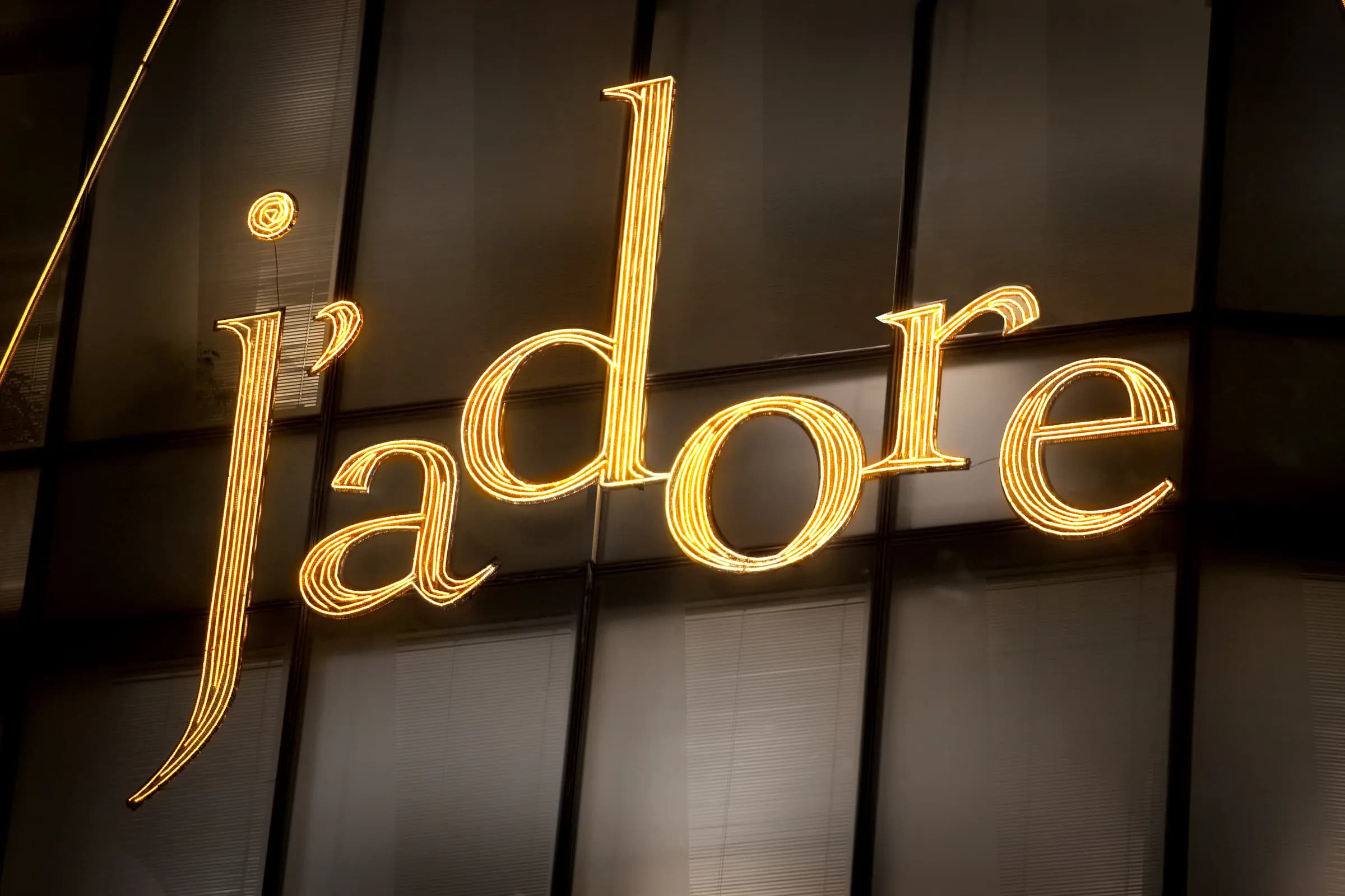 Illuminated gold J'adore script on the Dior 57th Street flagship facade at night, New York
