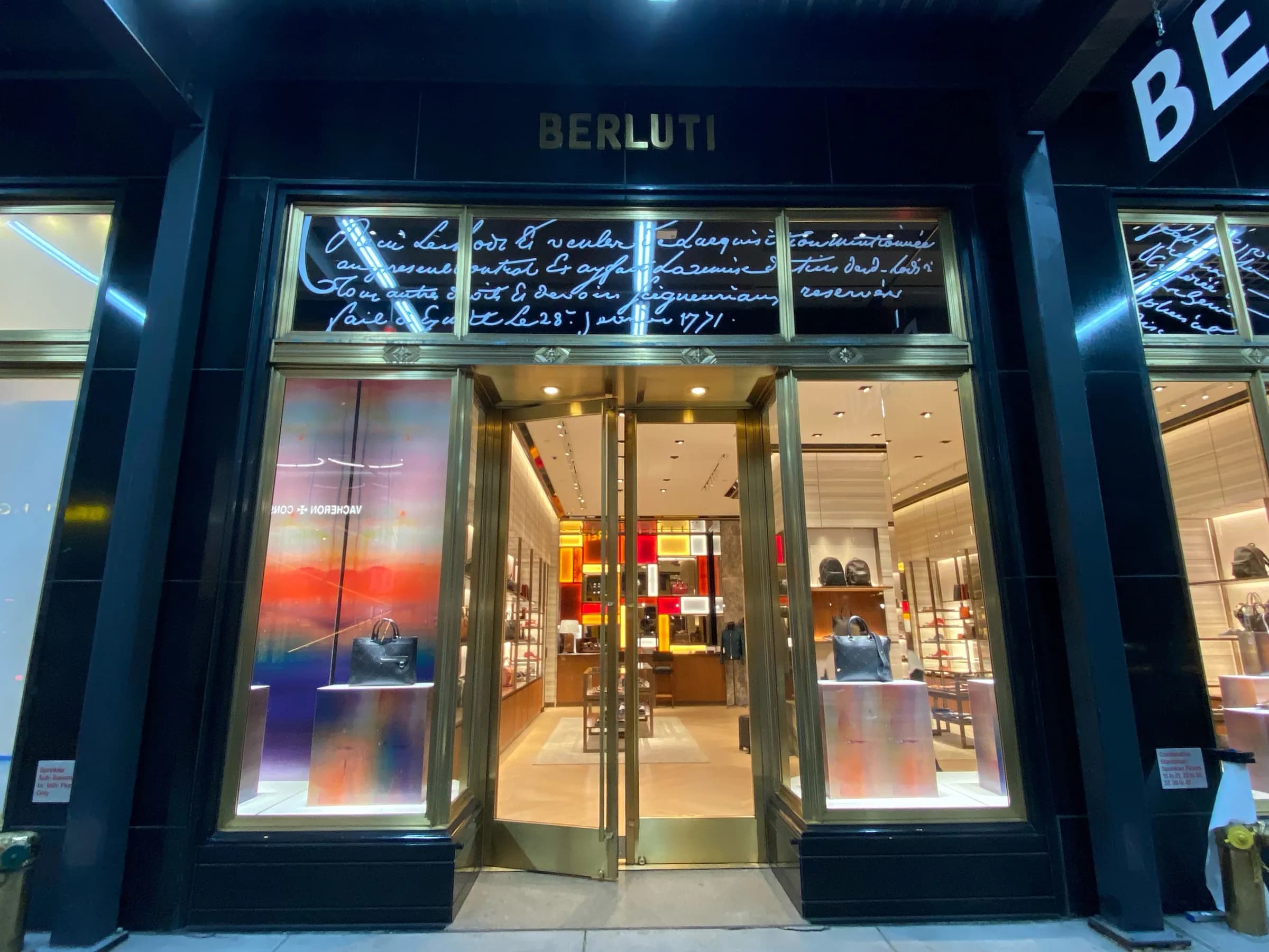 Berluti New York storefront at night with calligraphic script graphics and gradient window displays