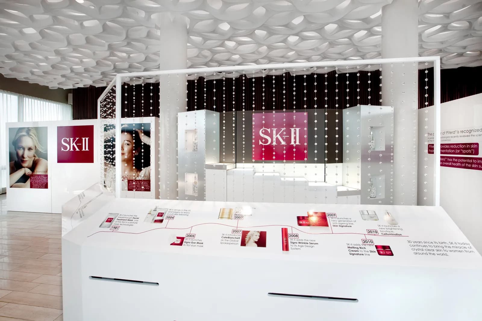 Minimal white SK-II pop-up with red product displays and backlit logo panels