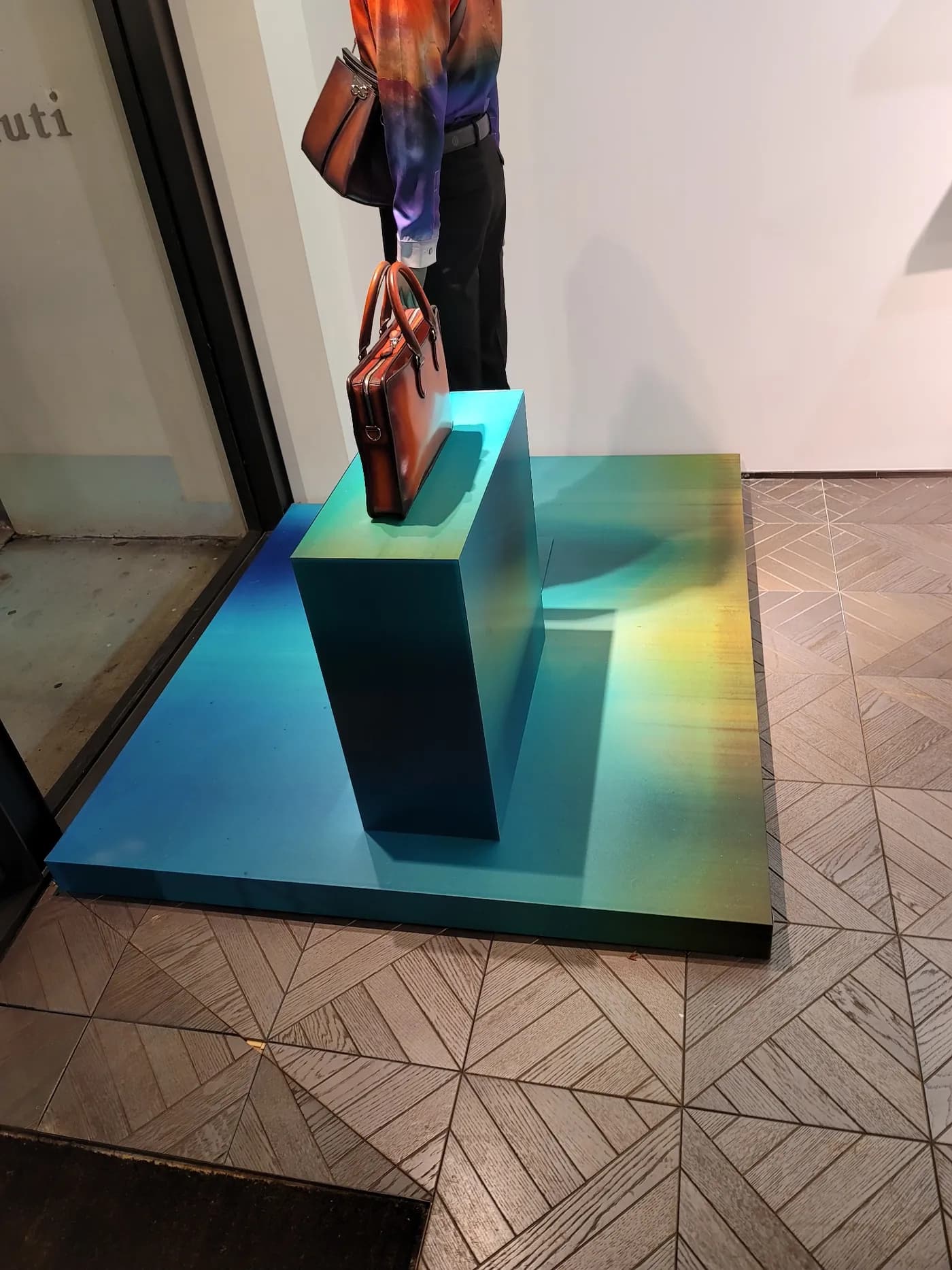 Iridescent gradient plinths displaying Berluti leather goods