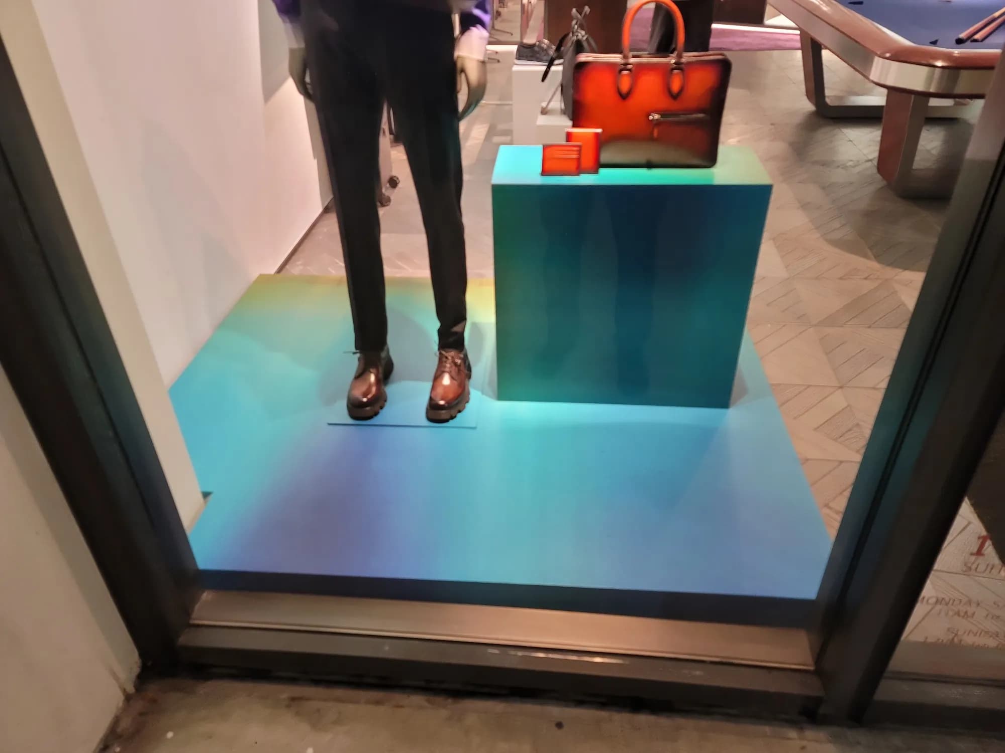 Iridescent teal platform with a Berluti bag and mannequin in the window