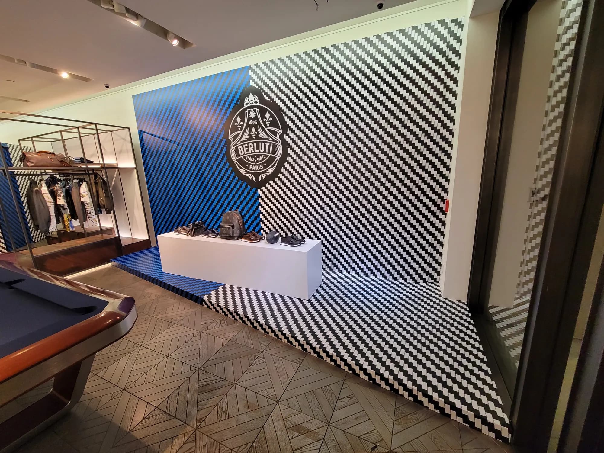 Berluti May 2021 installation with blue crest wall and black-and-white checkered platform