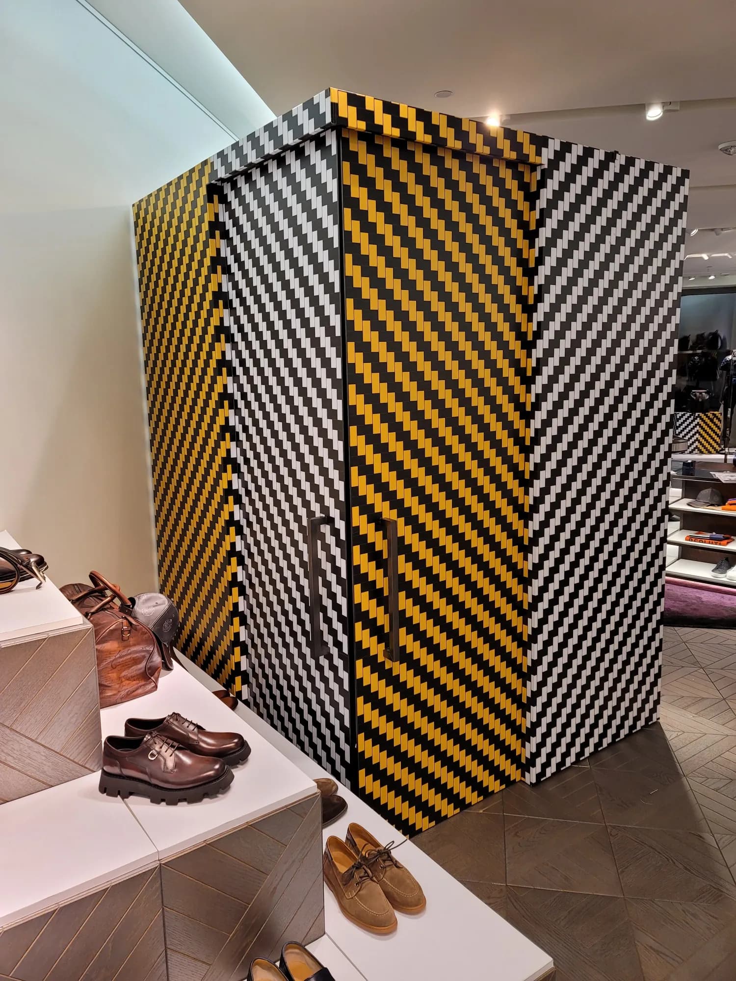 Berluti booth wrapped in black and ochre diagonal stripes with shoe display