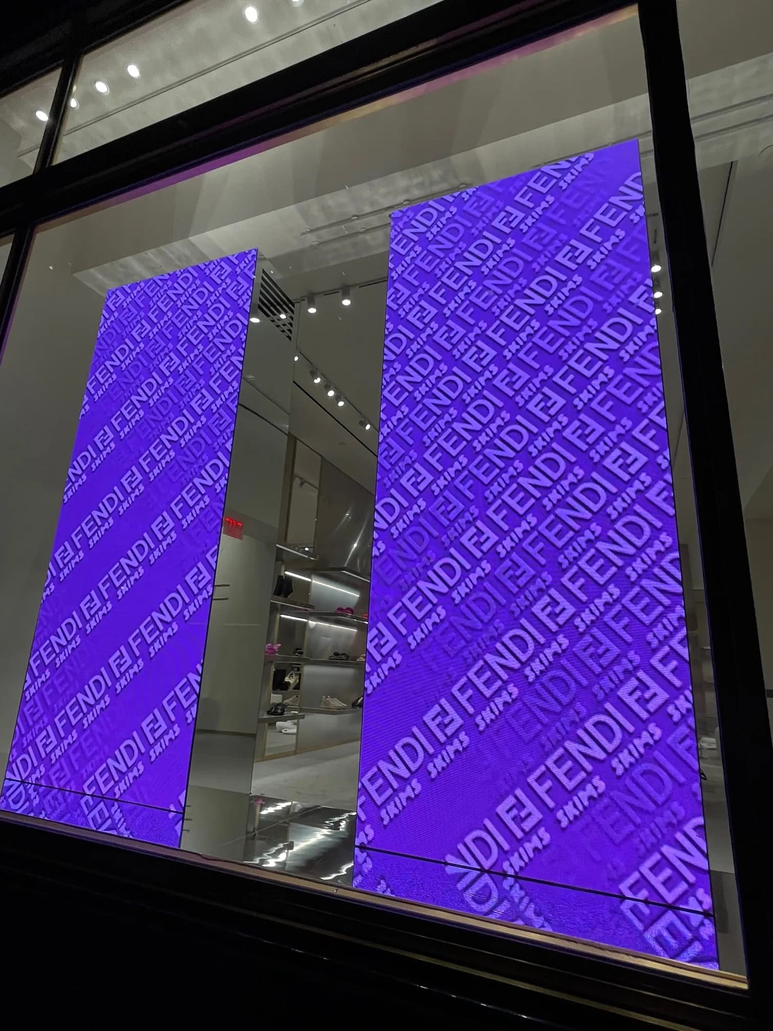 Close view of a Fendi x Skims LED screen glowing violet with repeating FENDI type, 57th Street