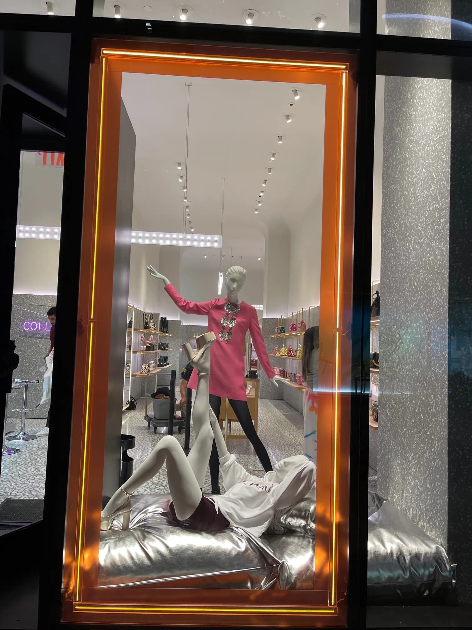 Valentino window framed in orange neon with Party Collection looks on silver cushions
