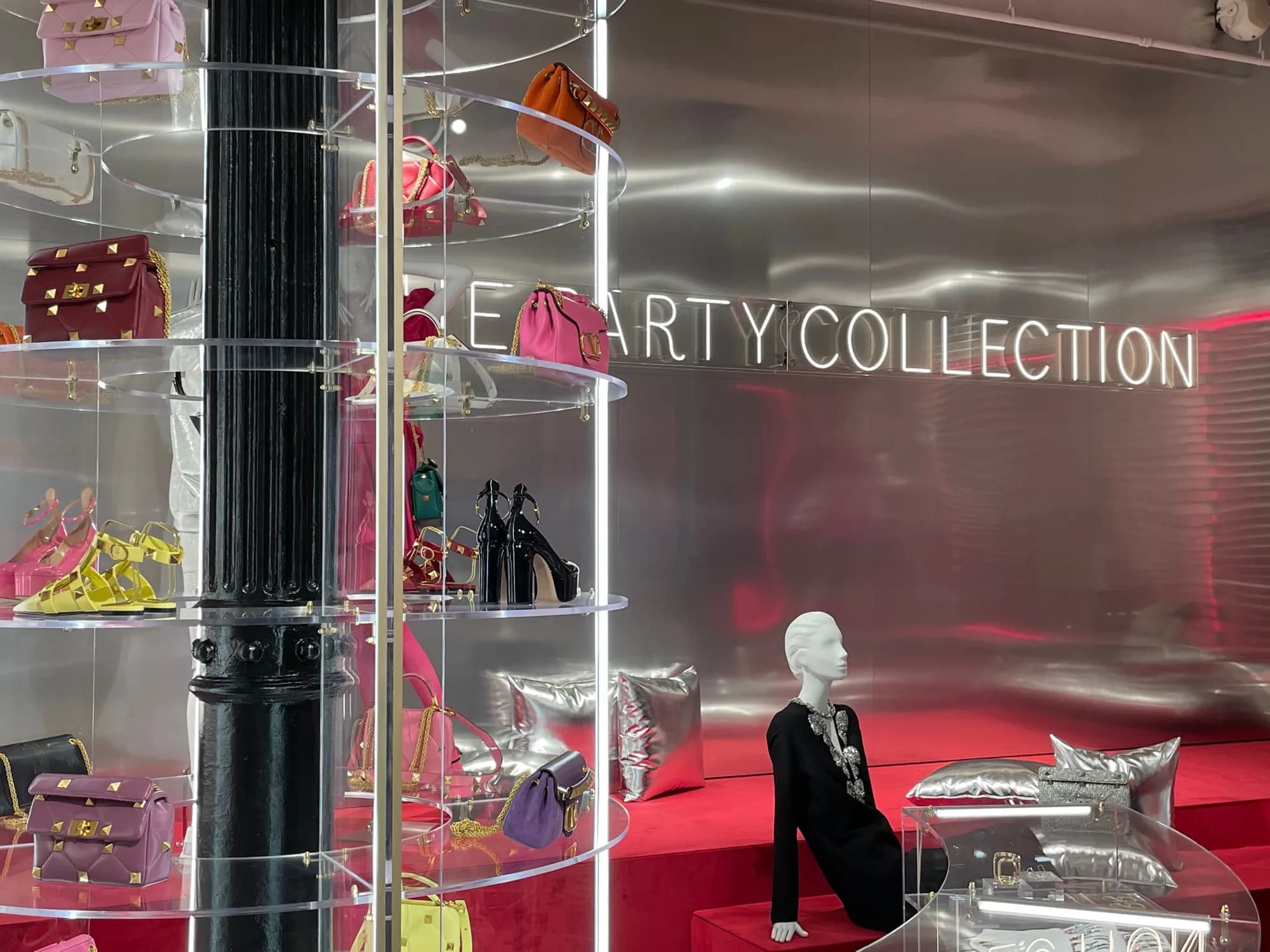 Clear acrylic tower displays of Valentino bags and shoes against a Party Collection wall, Soho