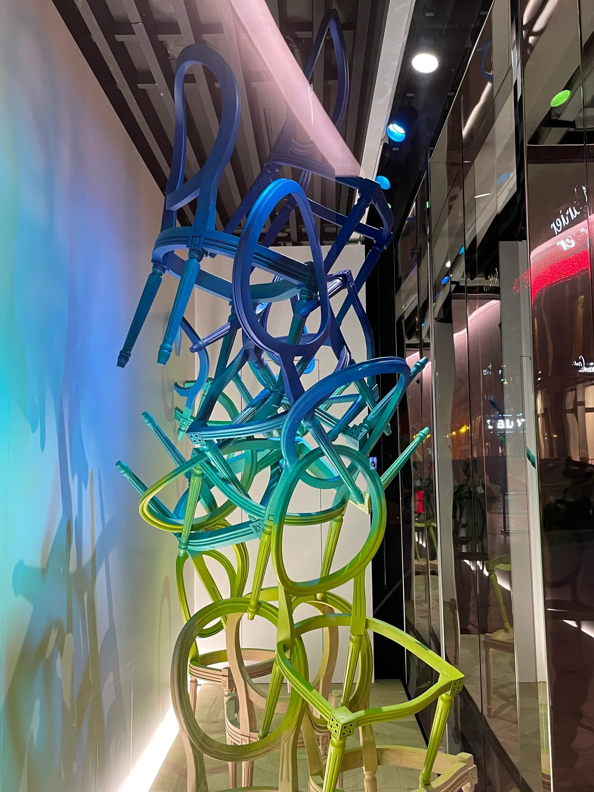 Dior chair installation for Art Miami, iridescent chairs in blue, green and gold cascading down a wall