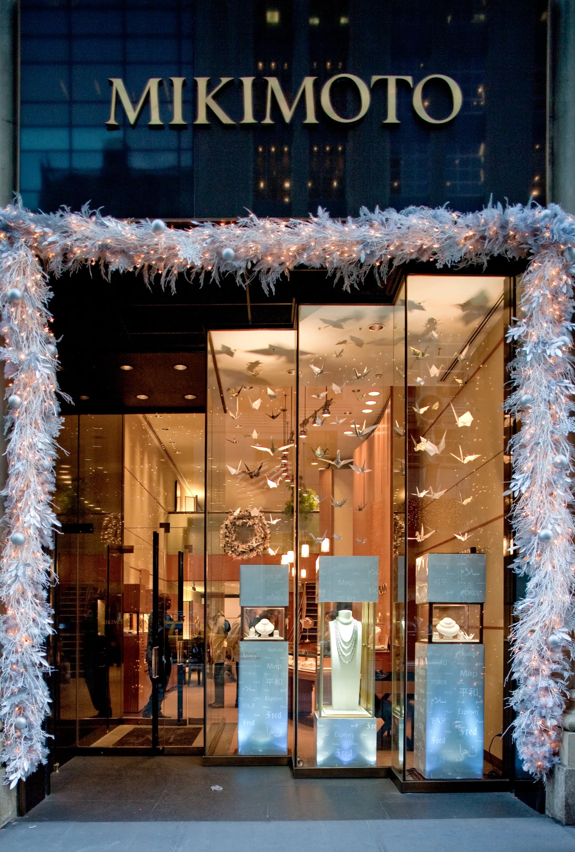 Mikimoto boutique entrance framed by a white feathered holiday arch with lit windows