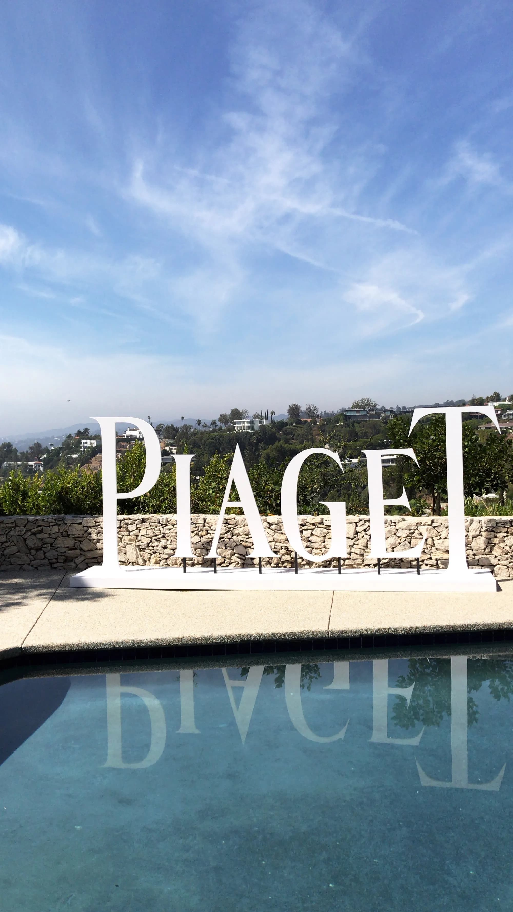Six-foot Piaget logo letters standing beside a reflecting pool